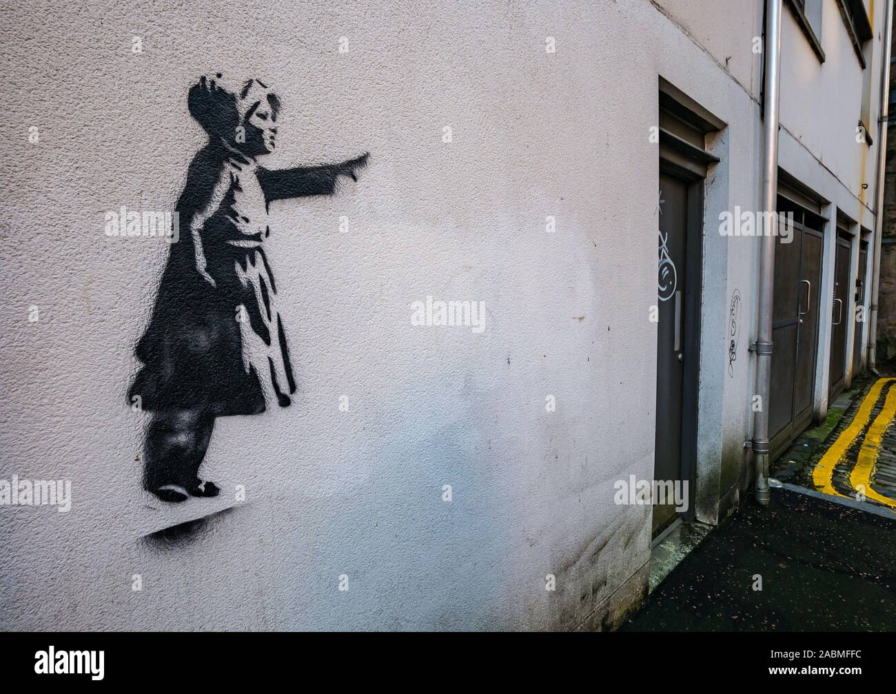 Tron Square, Edinburgh, Scotland, United Kingdom, 28th November 2019. Real of fake Banksy? A stencil of a young girl pointing is discovered on a wall in a quiet narrow cobbled lane. A number of Banksy style stencil images have appeared around the city over the last year but it is unclear whether they are real or copycats Stock Photo