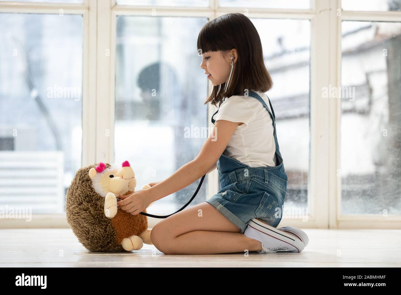 Little girl use stethoscope curing toy hedgehog Stock Photo