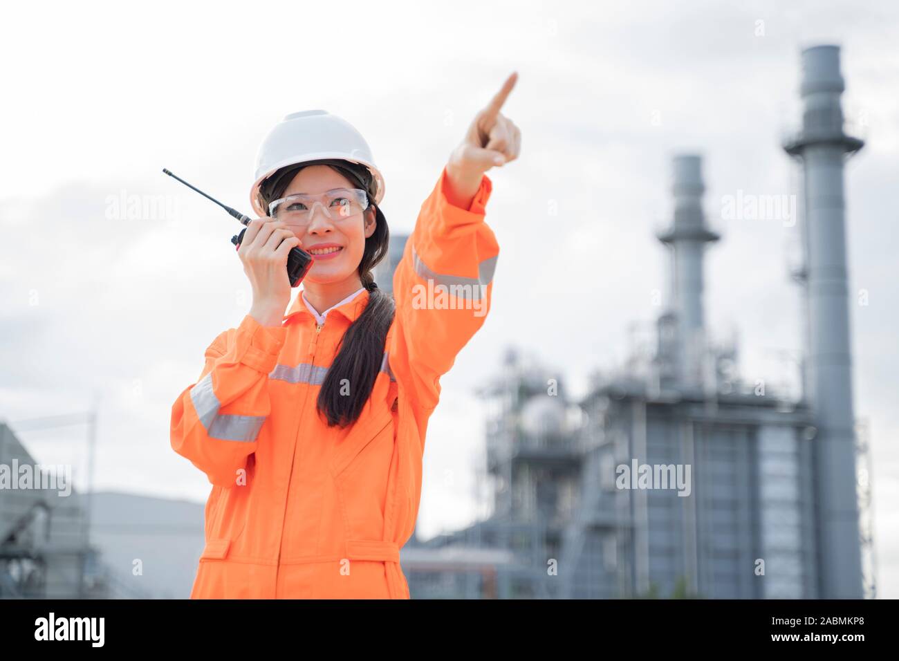 Asian female engineer with a radio is working outside the factory. Stock Photo
