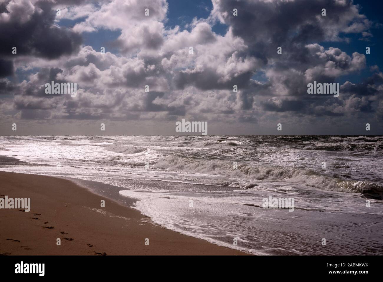 Wolken im Gegenlicht ueber Strand und Meer bei stuermischer See Stock Photo