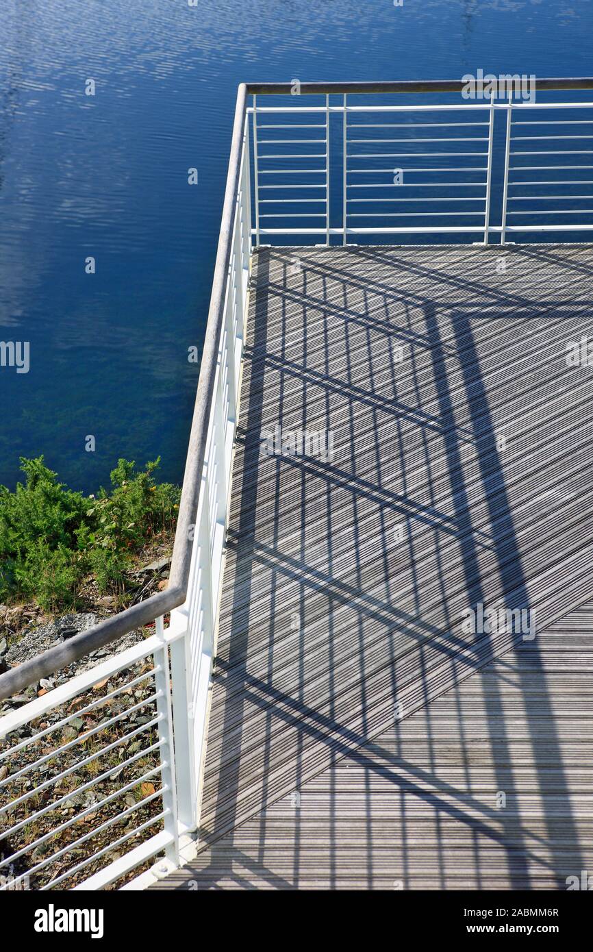 Shadows of balcony railings on a wooden walkway Stock Photo