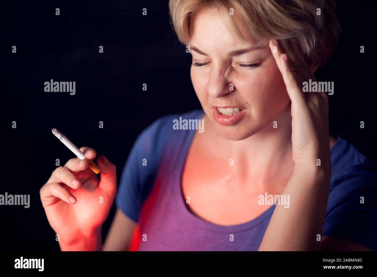 Woman smokes cigarette and has strong headache. Tobacco addiction and