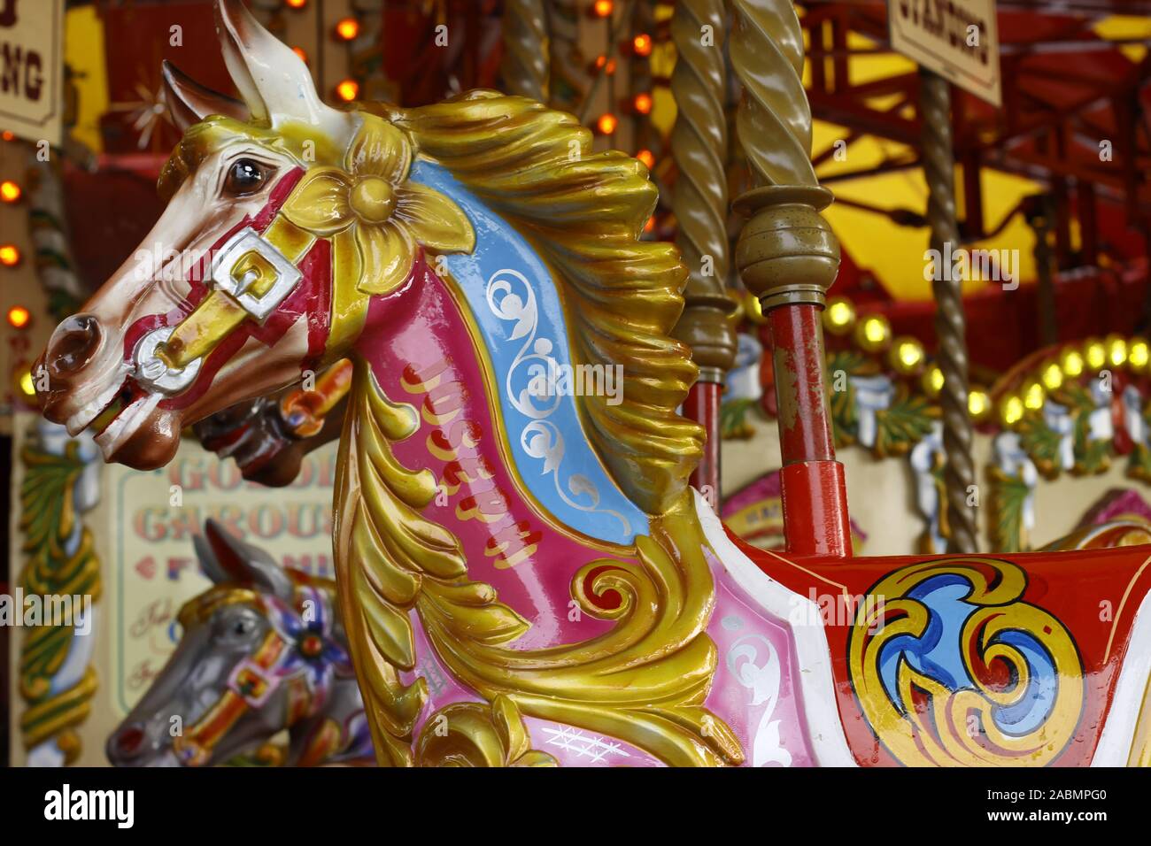 merry go round or carousel at a fairground showing detail of brightly painted horses etc Stock Photo