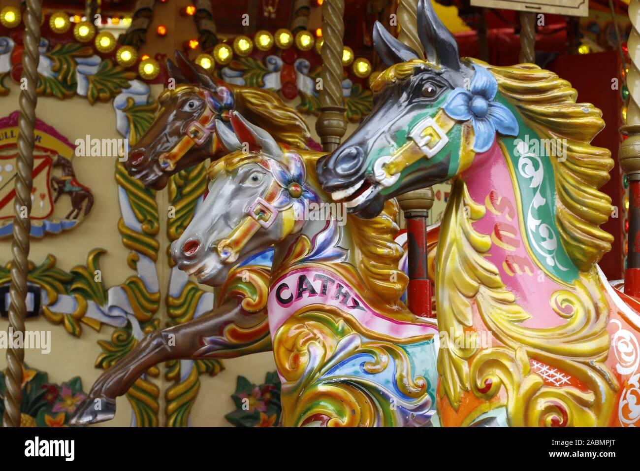 merry go round or carousel at a fairground showing detail of brightly painted horses etc Stock Photo