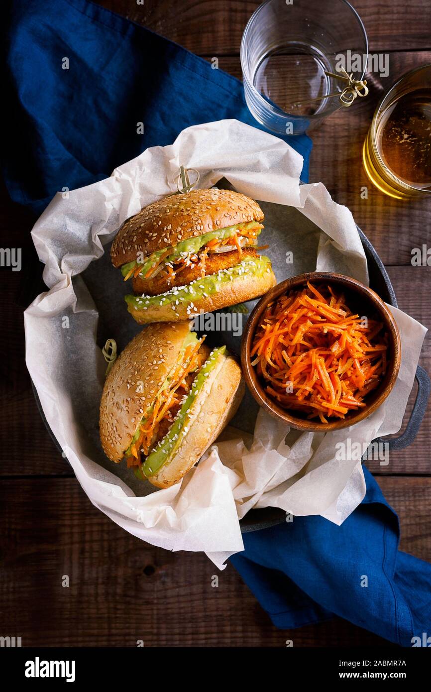 Vegan sweet potato chickpea burgers with avocado guacamole sauce and carrot slaw on wooden background top view.Vegetarian meal,plant based food Stock Photo