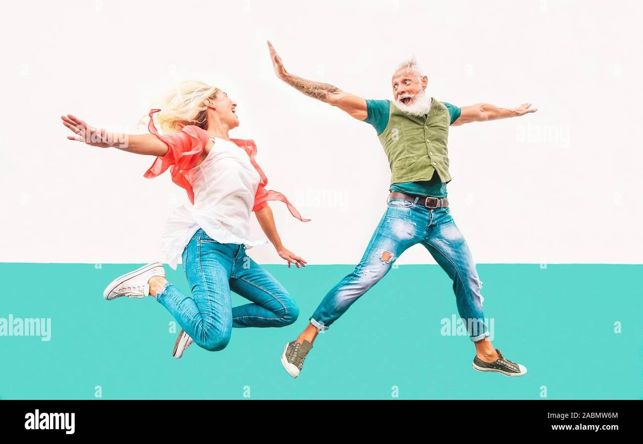 Happy crazy couple jumping together outdoor - Mature trendy people having fun celebrating and dancing outside Stock Photo