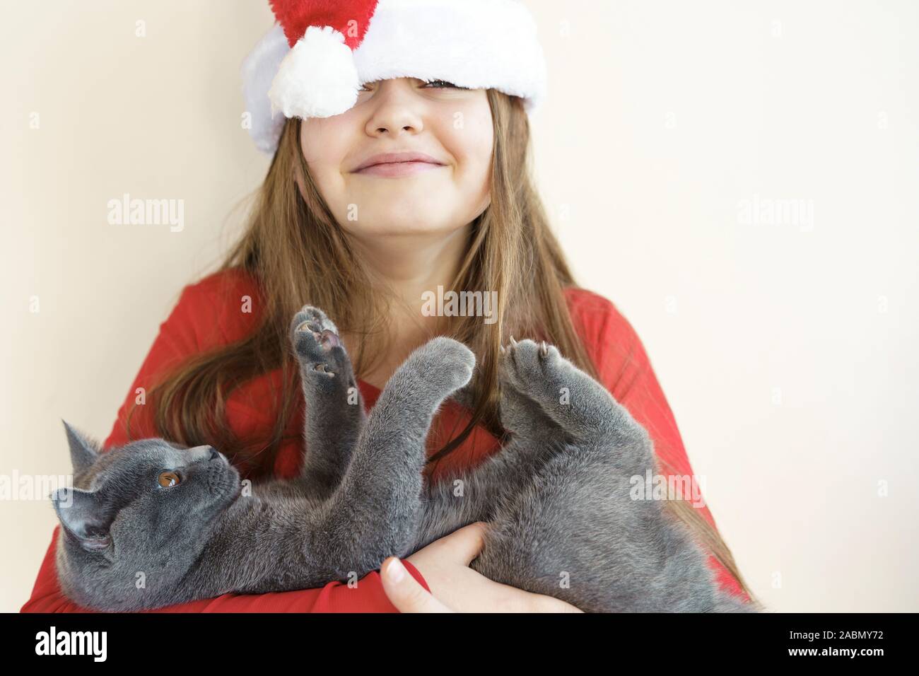 A teenager girl in a red fluffy Santa Claus hat and red sweater Stock Photo