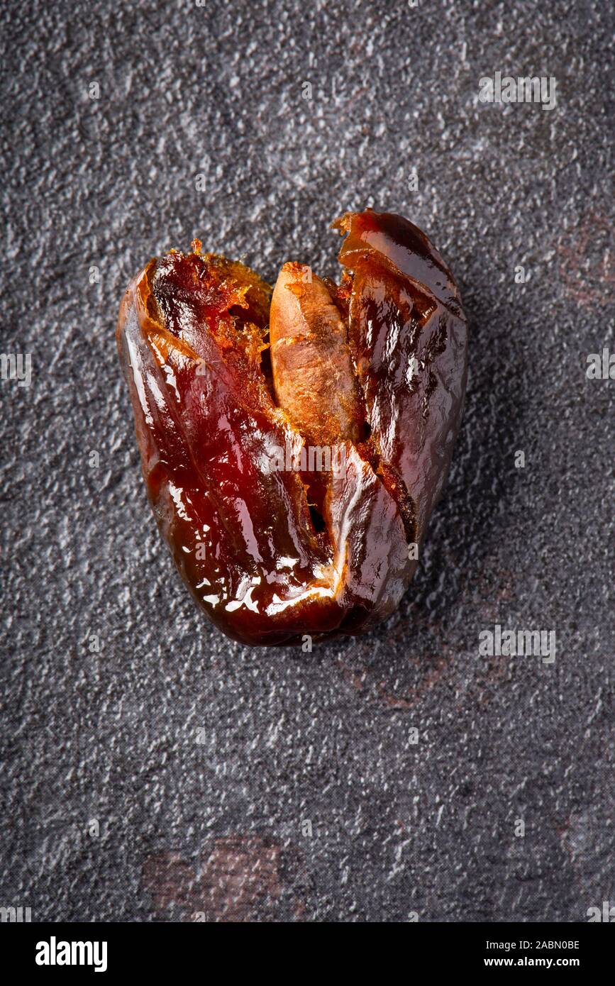high angle view of a smashed ripe date fruit on a dark gray stone surface Stock Photo