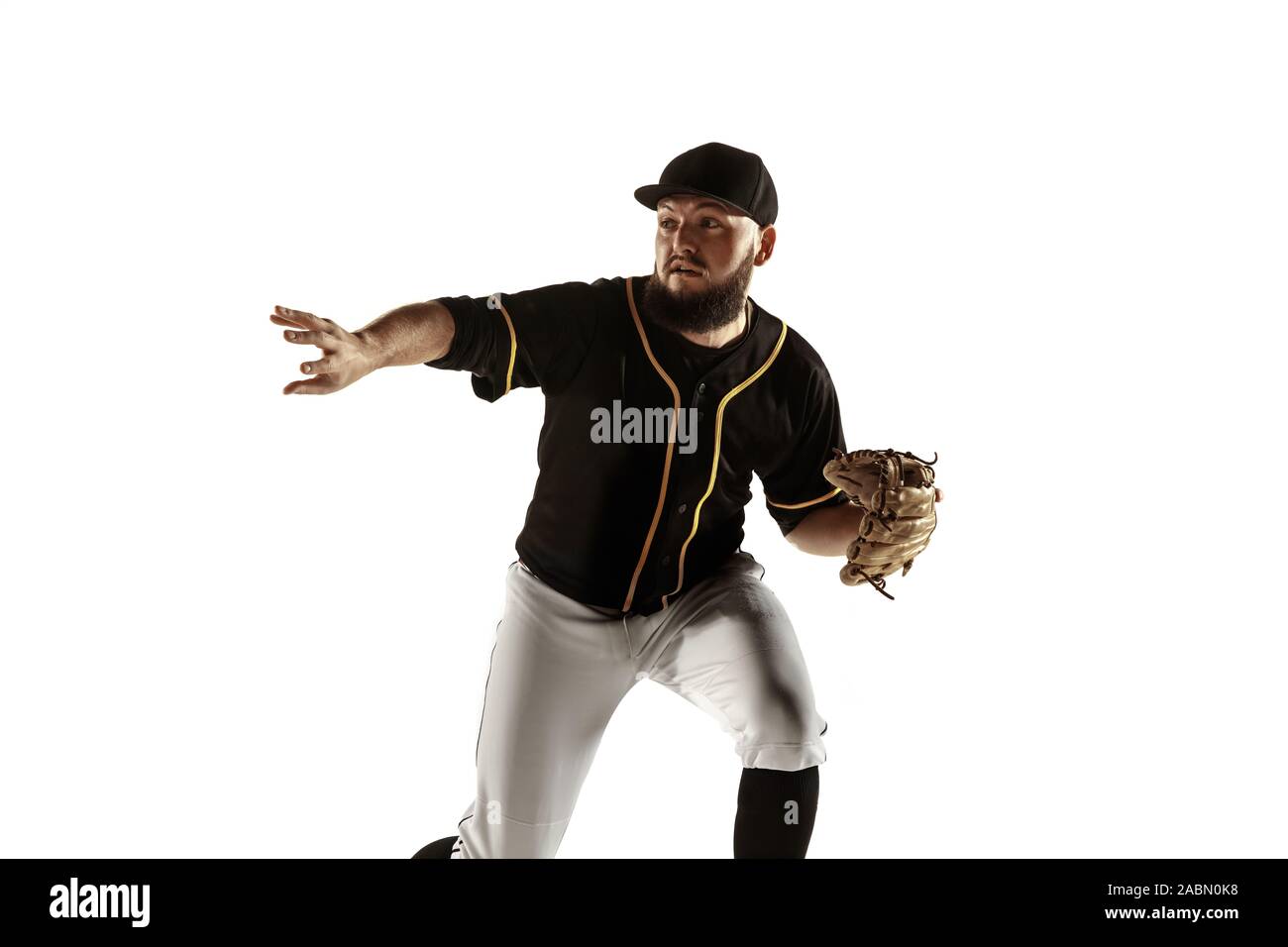Baseball player, pitcher in a black uniform practicing and training isolated on a white background. Young professional sportsman in action and motion. Healthy lifestyle, sport, movement concept. Stock Photo