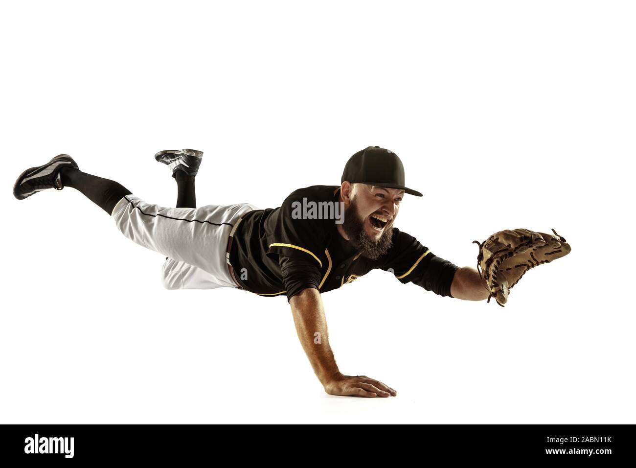 In flight. Baseball player, pitcher in black uniform practicing and training isolated on white background. Young professional sportsman in action and motion. Healthy lifestyle, sport, movement concept. Stock Photo