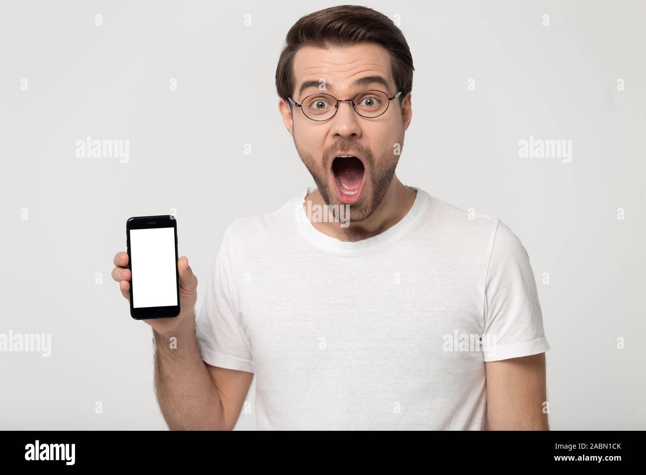 Amazed millennial guy in glasses show cellphone screen Stock Photo