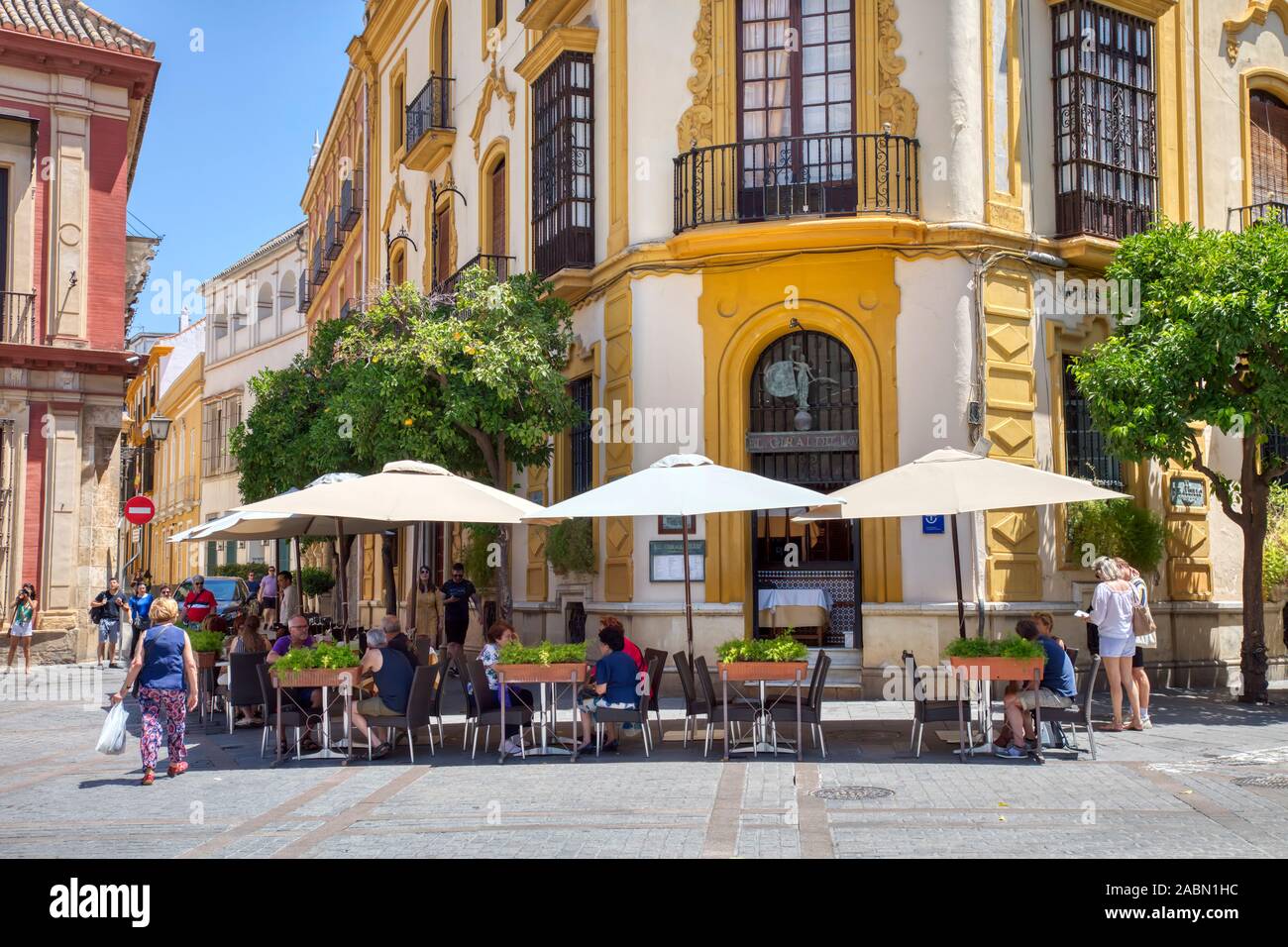 People enjoying outdoor sidewalk cafes in Santa Cruz or old Jewish Quarter of Seville Andulsia Spain Stock Photo