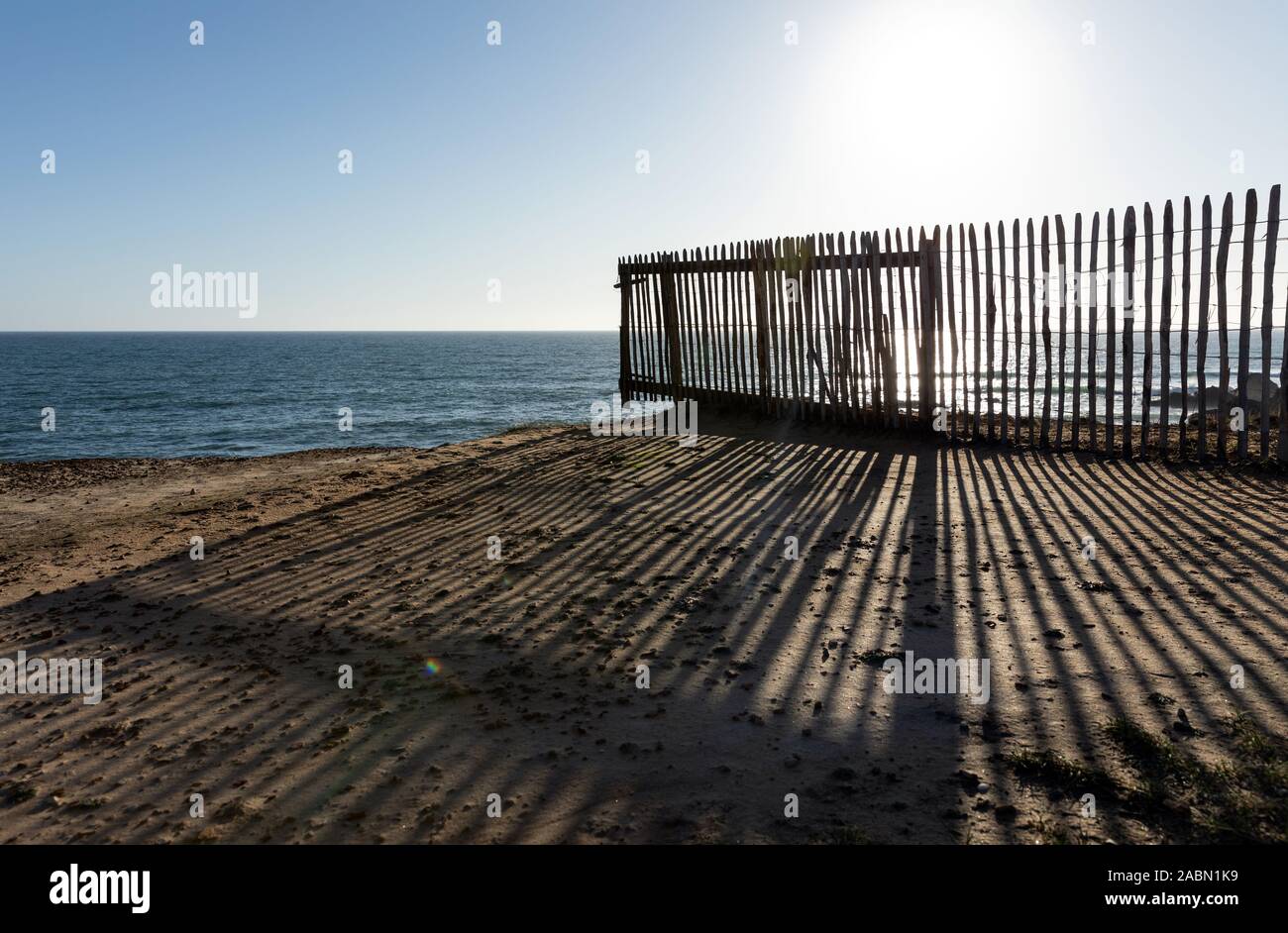 Wooden fence over the sea against the light (Jard-sur-Mer, France) Stock Photo
