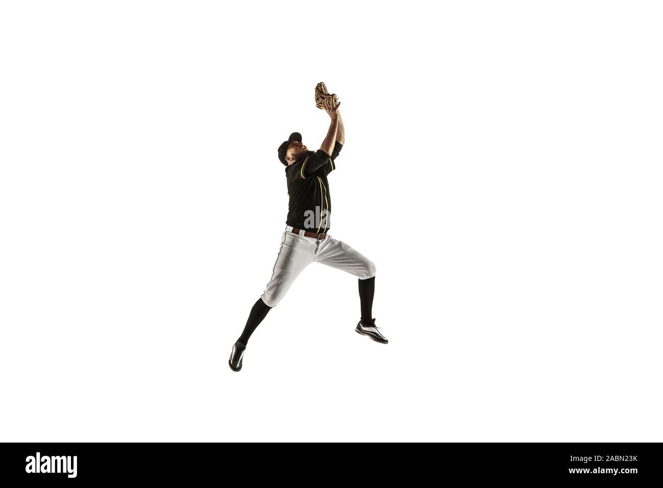 In jump. Baseball player, pitcher in black uniform practicing and training isolated on white background. Young professional sportsman in action and motion. Healthy lifestyle, sport, movement concept. Stock Photo