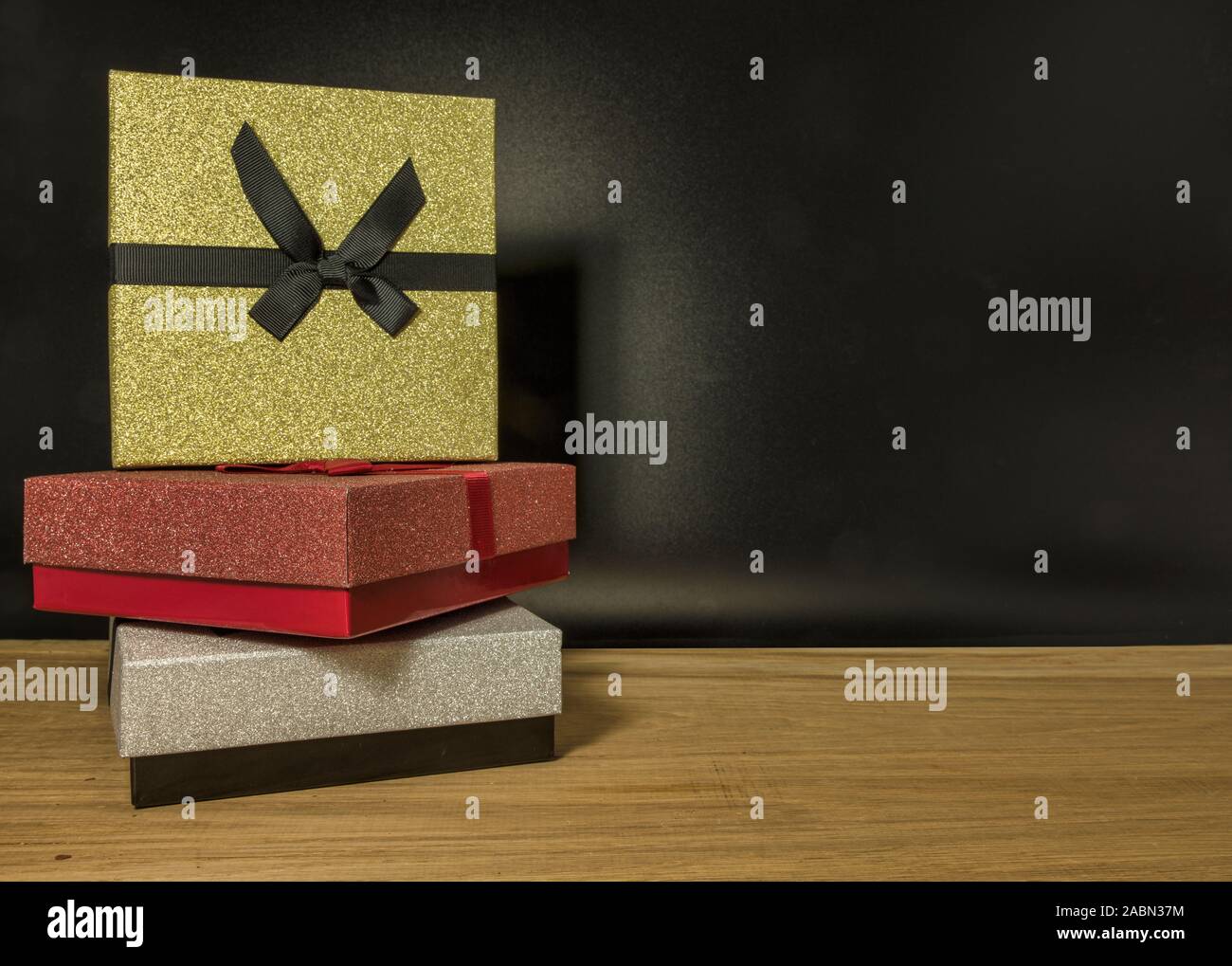 three gift boxes in red silver and gold on black background Stock Photo