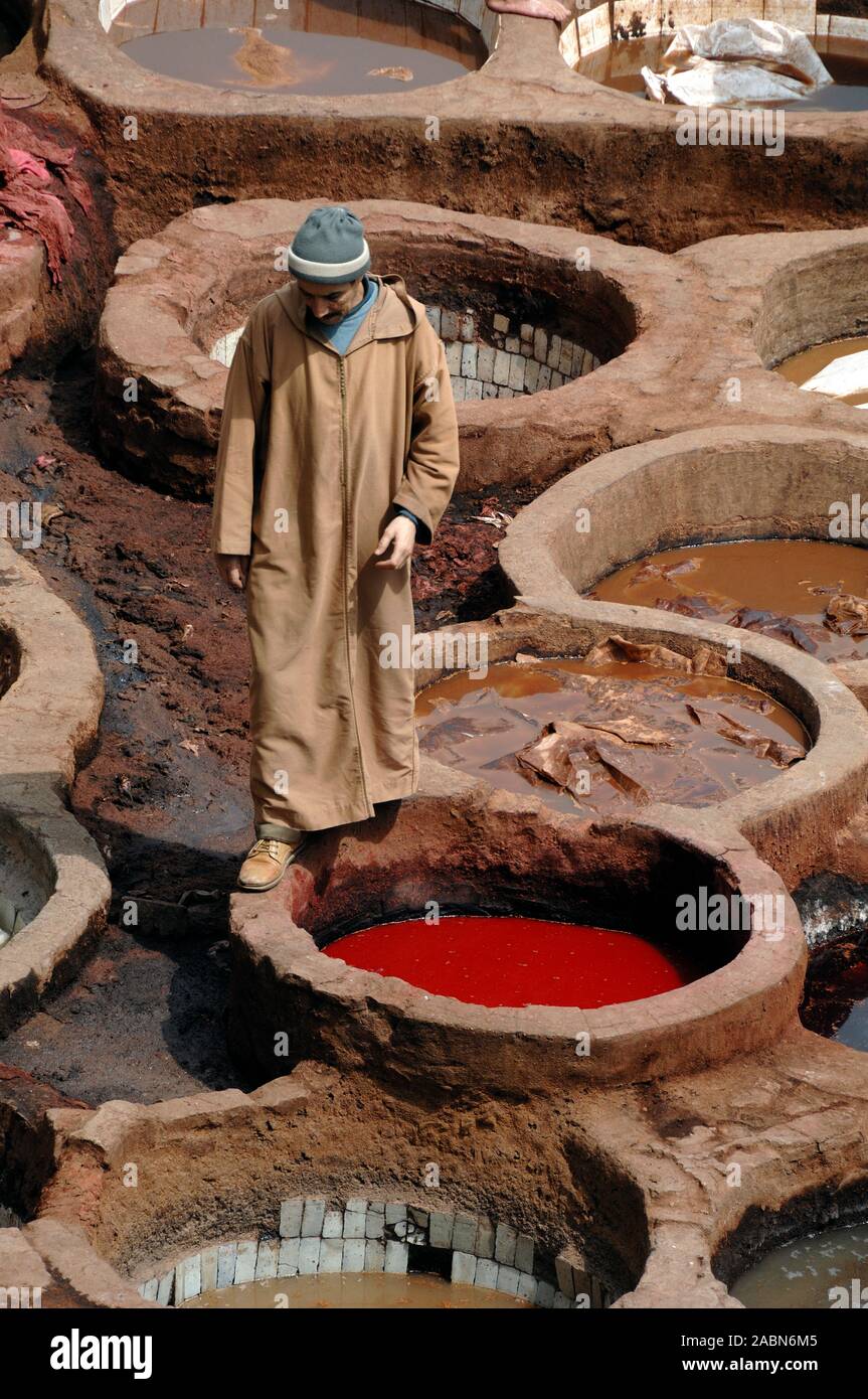 Moroccan Leather Worker Wearing Kaftan & Dying Pits incl. Red Poppy Dye at Chouara Tannery or Tanneries in the Fes el Bali District Fez or Fes Morocco Stock Photo