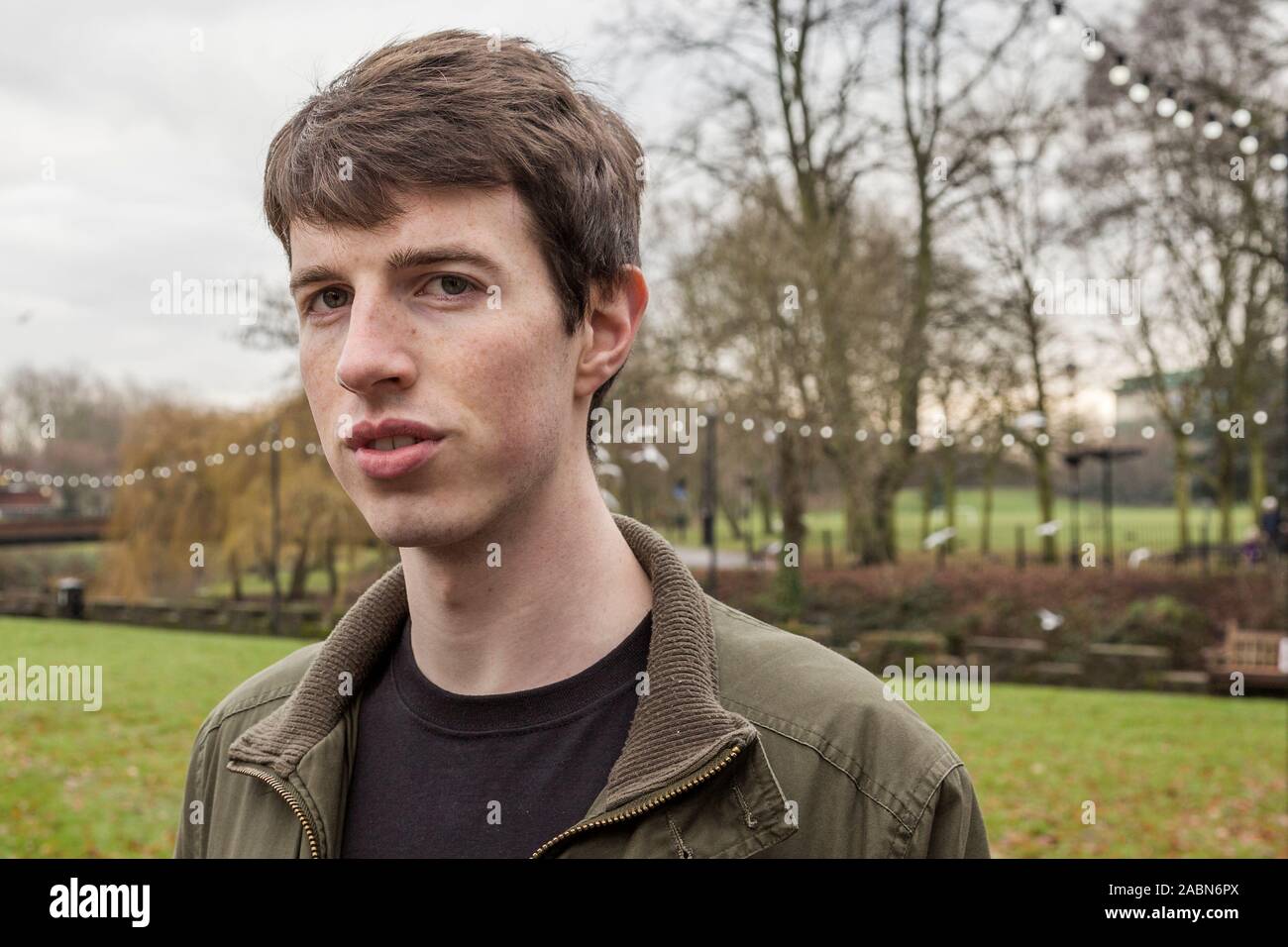 Close up head and shoulders of a young man in his late teens or early twenties walking in a park. Stock Photo