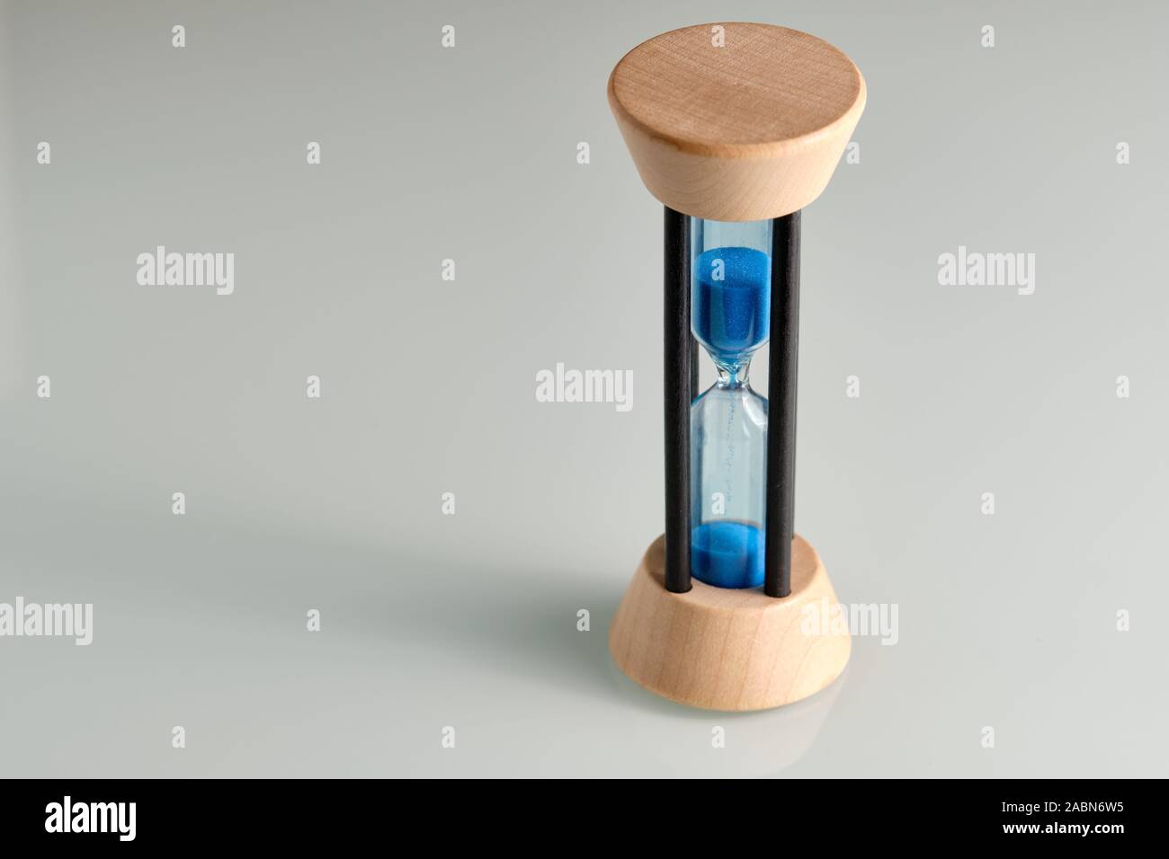 Hourglass made of wood and glass with blue sand running through while time is passing by Stock Photo