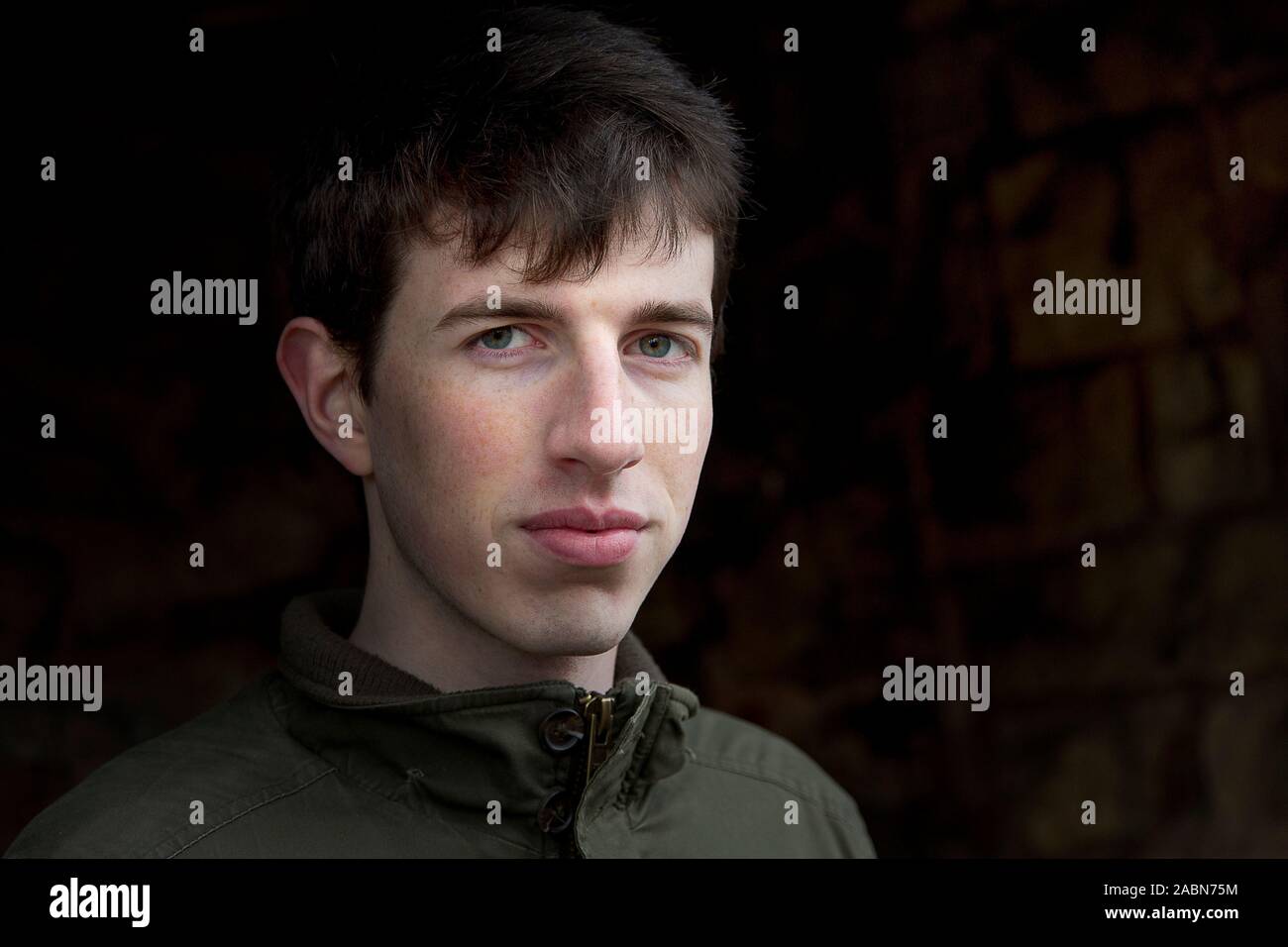Head shot of a handsome young man in his early twenties or late teens against a dark background. Stock Photo