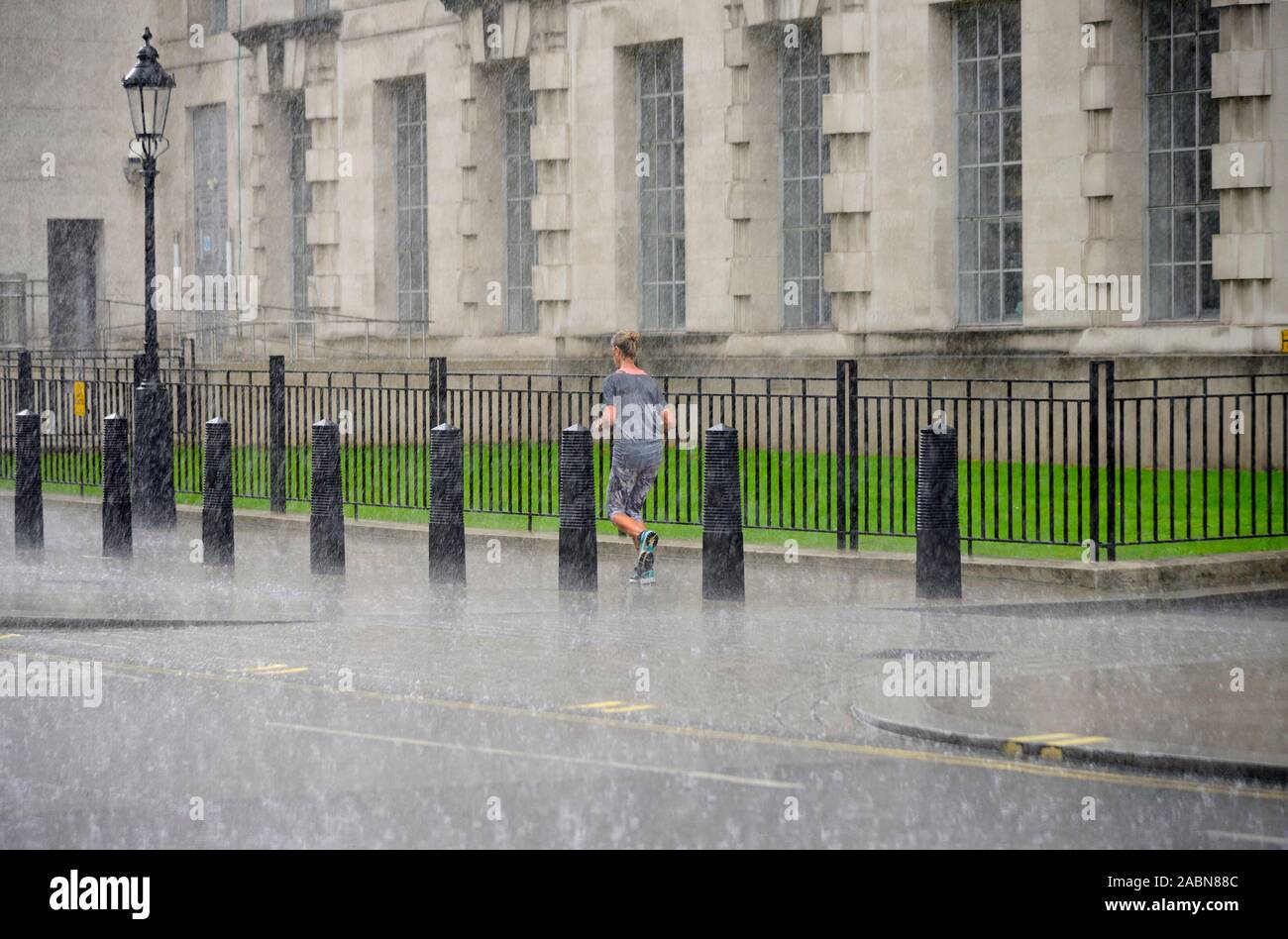 London, England, UK. Woman jogging in torrential rain Stock Photo