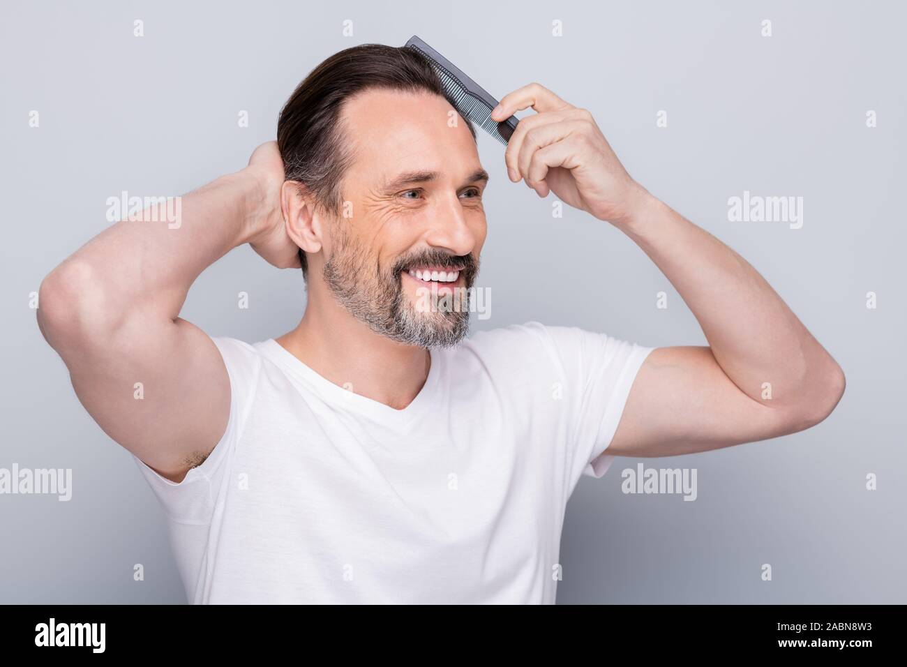 Closeup photo of macho cheerful mature guy holding new hairbrush try  quality of product on himself feel good result on hairstyle wear white  t-shirt Stock Photo - Alamy