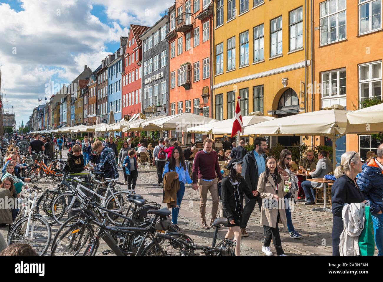 Copenhagen Denmark, view of tourists strolling along the cafe lined quayside in the colorful Nyhavn harbor area of Copenhagen, Denmark. Stock Photo