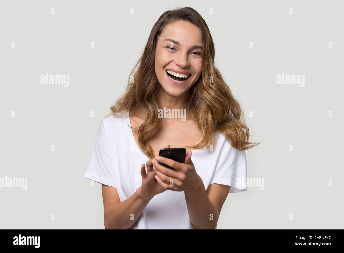Happy laughing young woman using cellphone apps, having fun Stock Photo