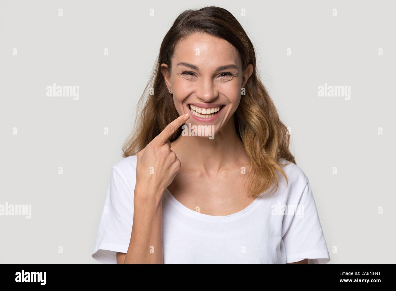 Happy young woman pointing finger at toothy healthy smile Stock Photo