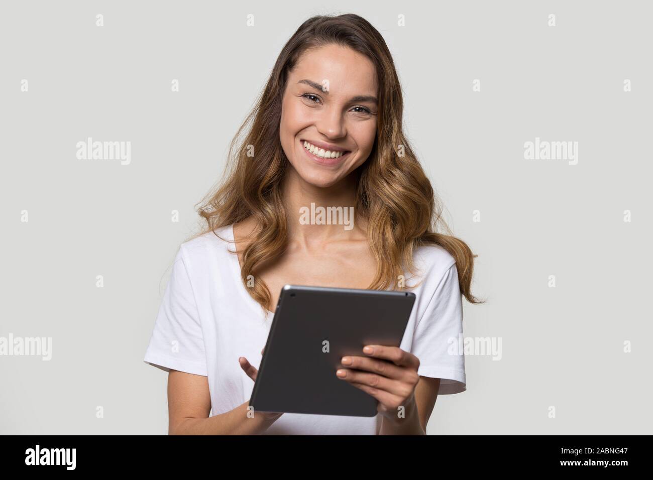 Happy smiling young woman using tablet computer, looking at camera Stock Photo