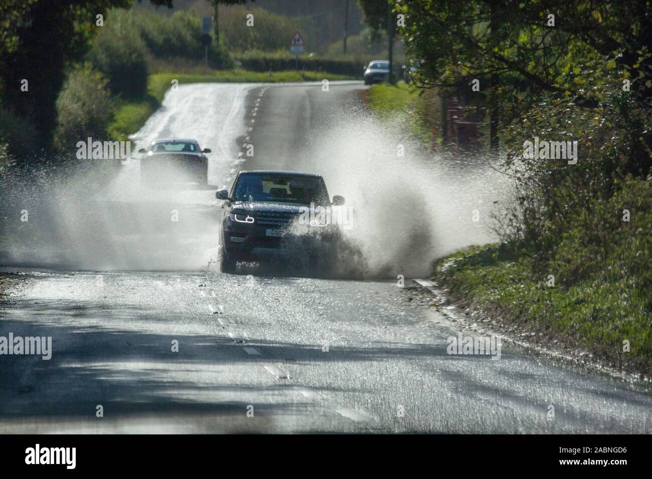 Person driving car  through flooded road in the Cheshire countryside near Knutsford after the heavy rain of the Autumn of 2019 Stock Photo
