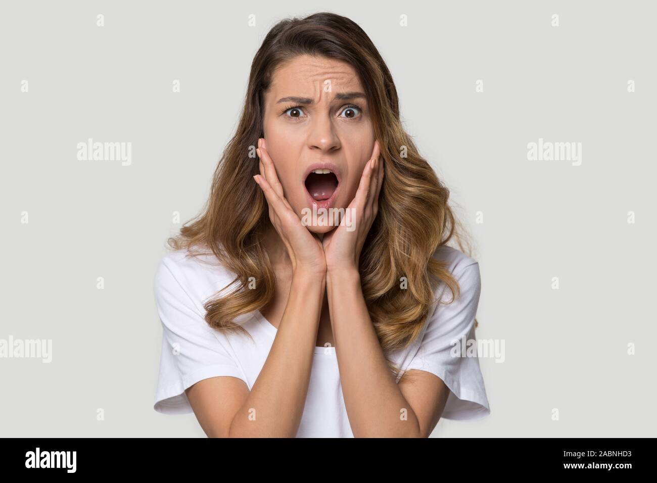 Shocked scared woman screaming, feeling afraid, looking at camera Stock Photo