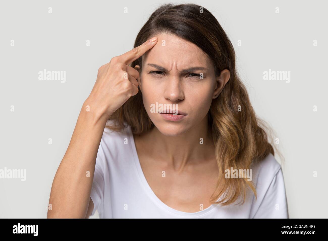Unhappy young woman touching forehead, worried about acne or wrinkle Stock Photo