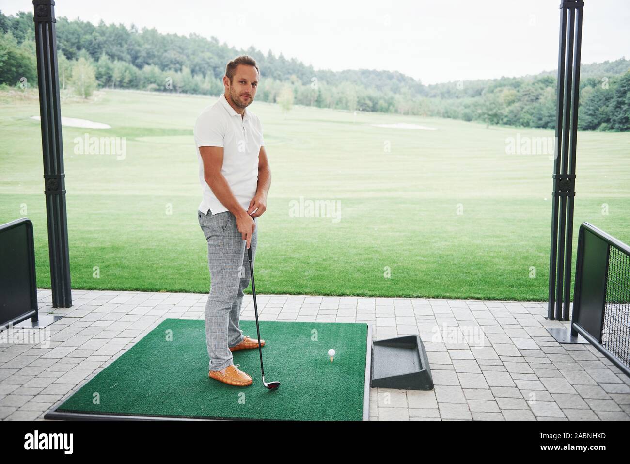 Pro golf player aiming shot with club on course. Male golfer on putting green about to take the shot Stock Photo