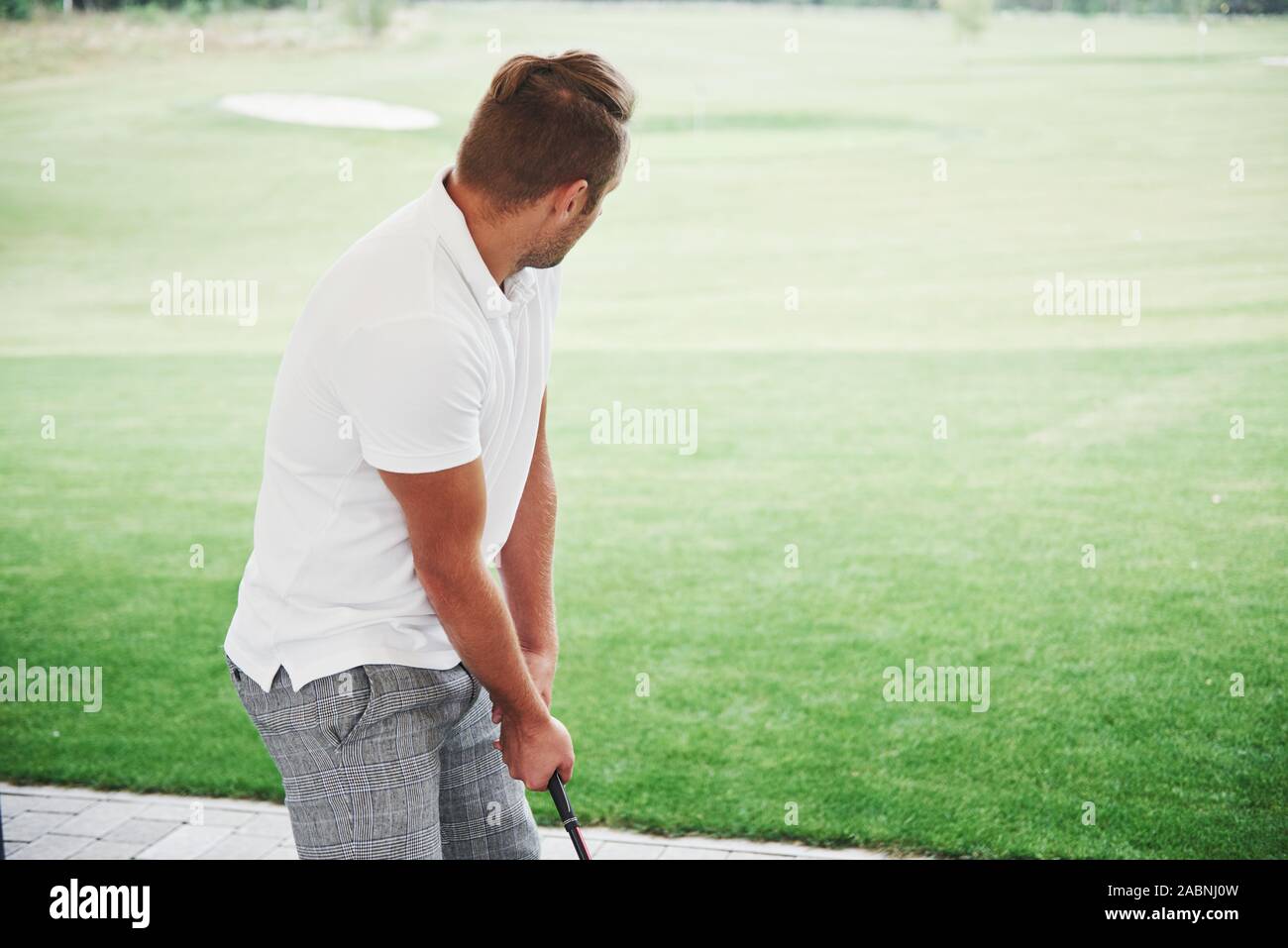 Pro golf player aiming shot with club on course. Male golfer on putting green about to take the shot, rear view Stock Photo