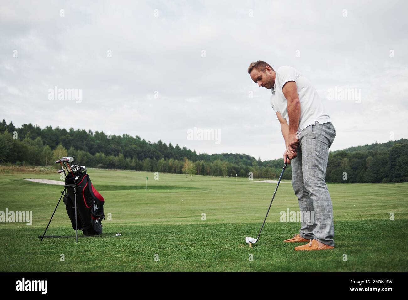 Pro golf player aiming shot with club on course. Male golfer on putting green about to take the hit Stock Photo