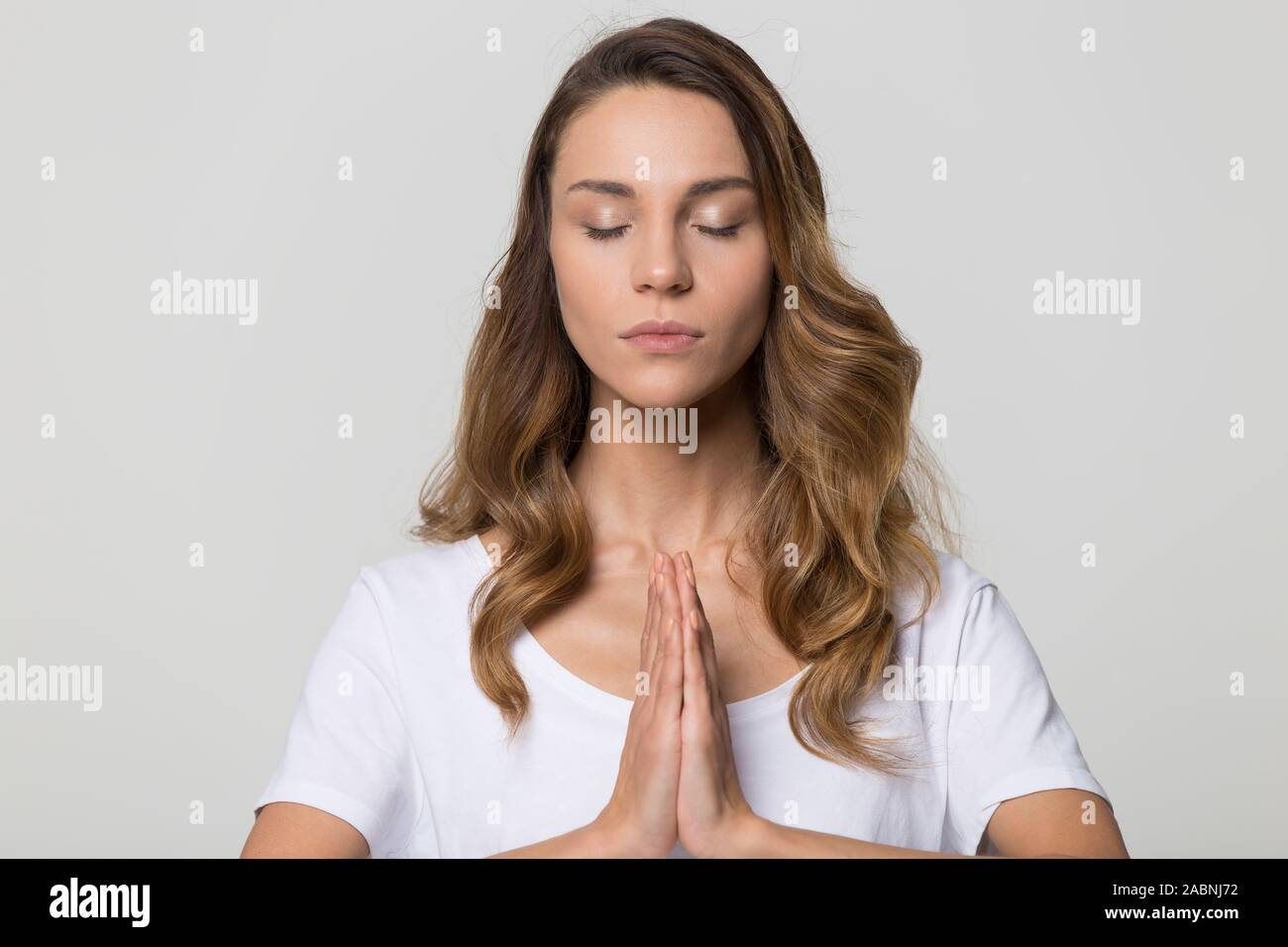 Calm peaceful woman with closed eyes meditating, practicing yoga Stock Photo