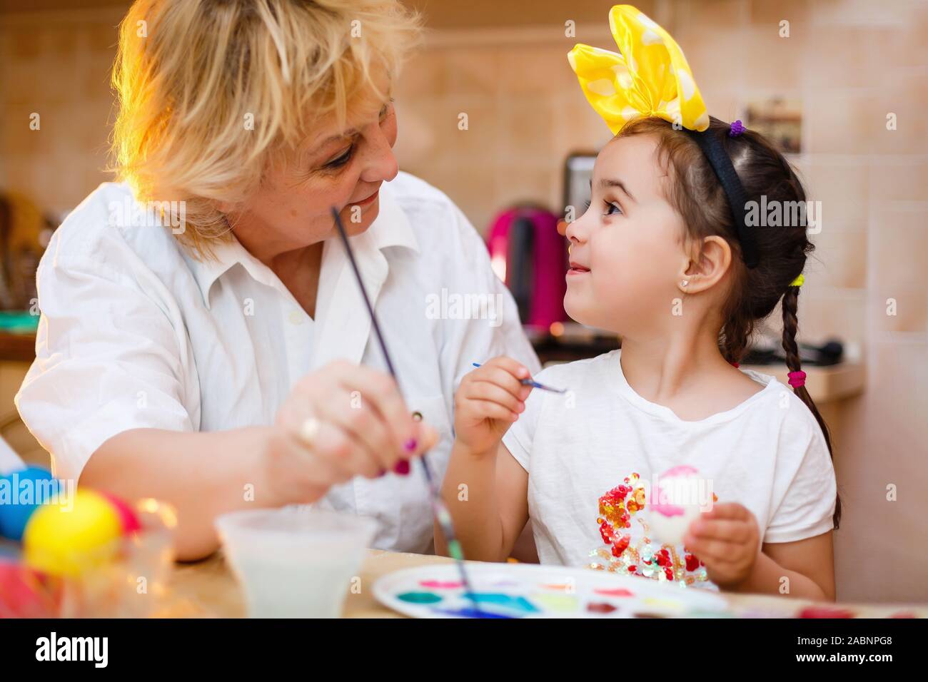 Grandmother painting eggs with granddaughter Stock Photo