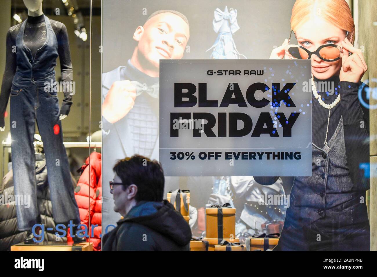 London, UK. 28 November 2019. A shopper outside the G-Star Raw store which  is promoting discounts in Oxford Street, the capital's busiest shopping  area, on the eve of Black Friday. The US