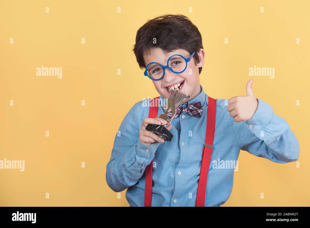 Happy boy with winning cup on yellow background Stock Photo