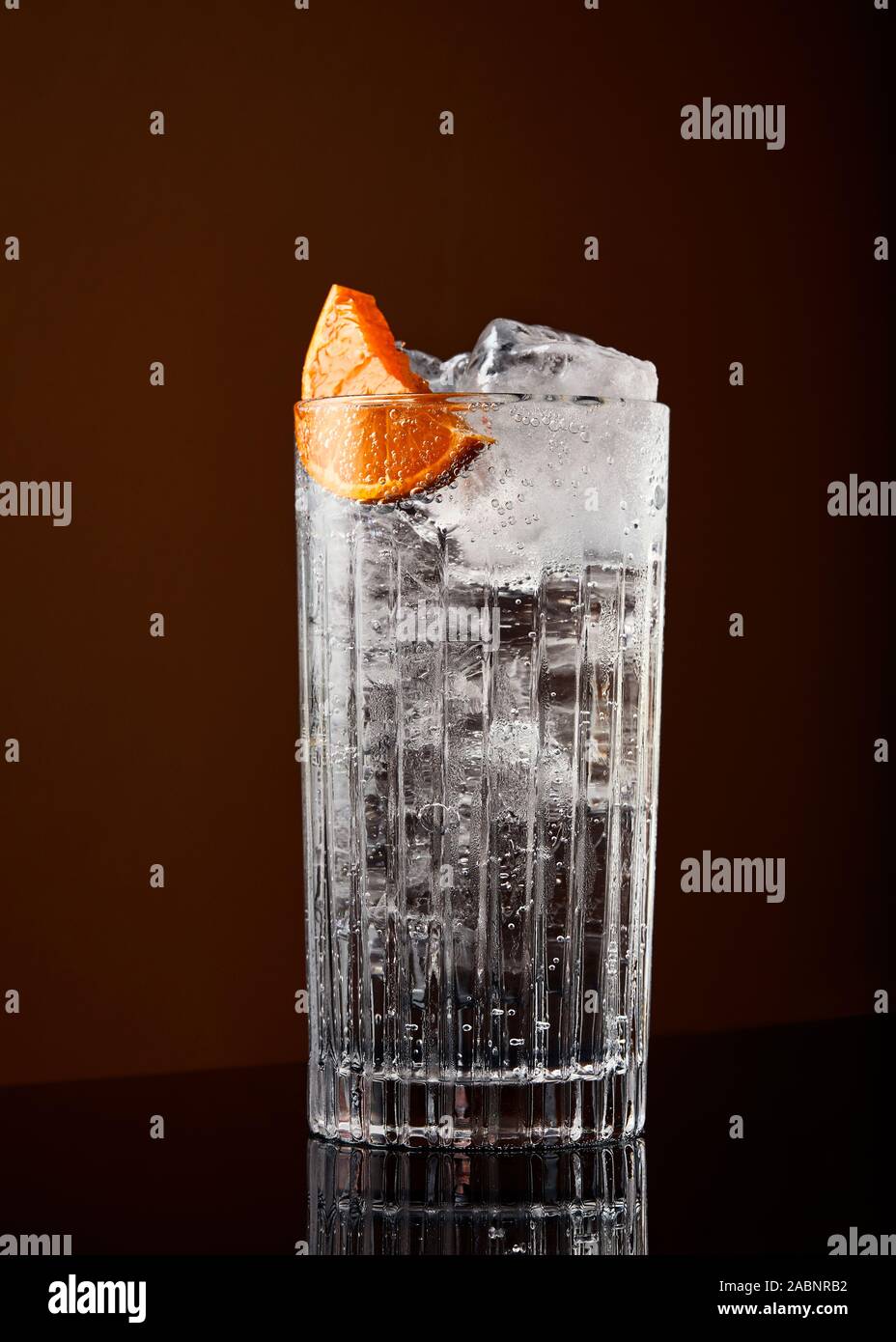 high ball gin and tonic with orange garnish against an orange background Stock Photo