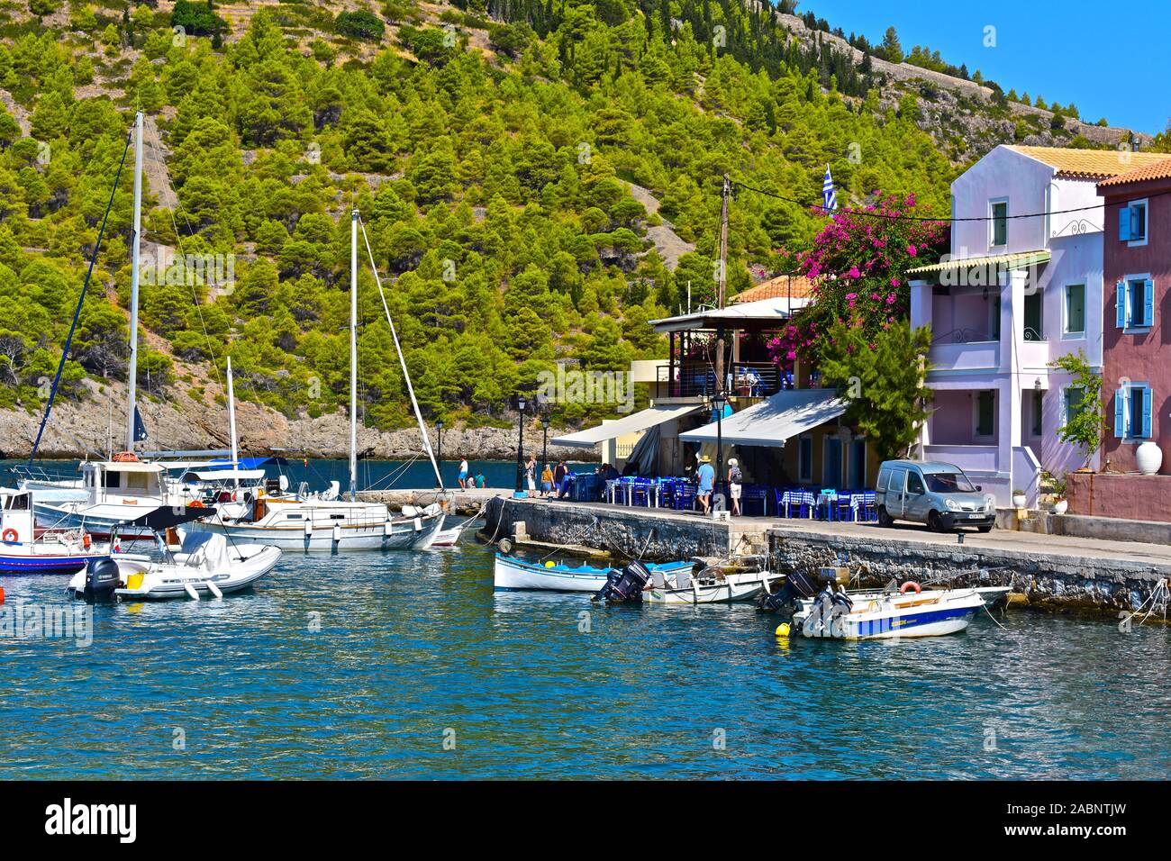 A view across the pretty natural harbour of the beautifulcoastal village of Assos. Leisure craft moored in front of harbourside restaurant cafés. Stock Photo