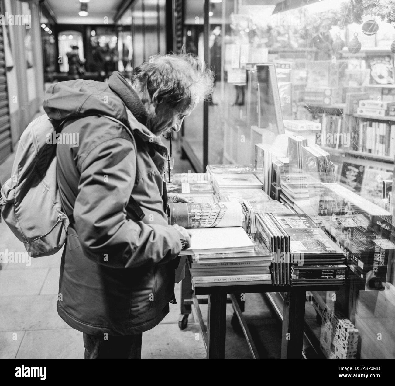 Strasbourg, France - Nov 23, 2017: Black and white Side view of mid-adult man reading a book on the outdoor shelves near the iconic Dinali library in Strasbourg Stock Photo