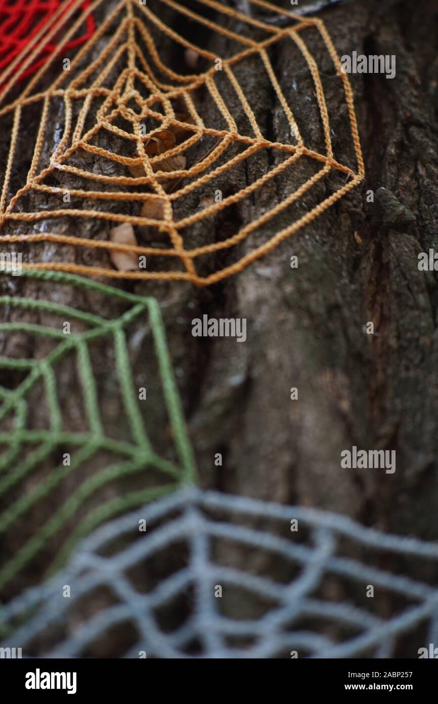 Knitted cobweb of colored threads on a tree trunk close-up Stock Photo ...
