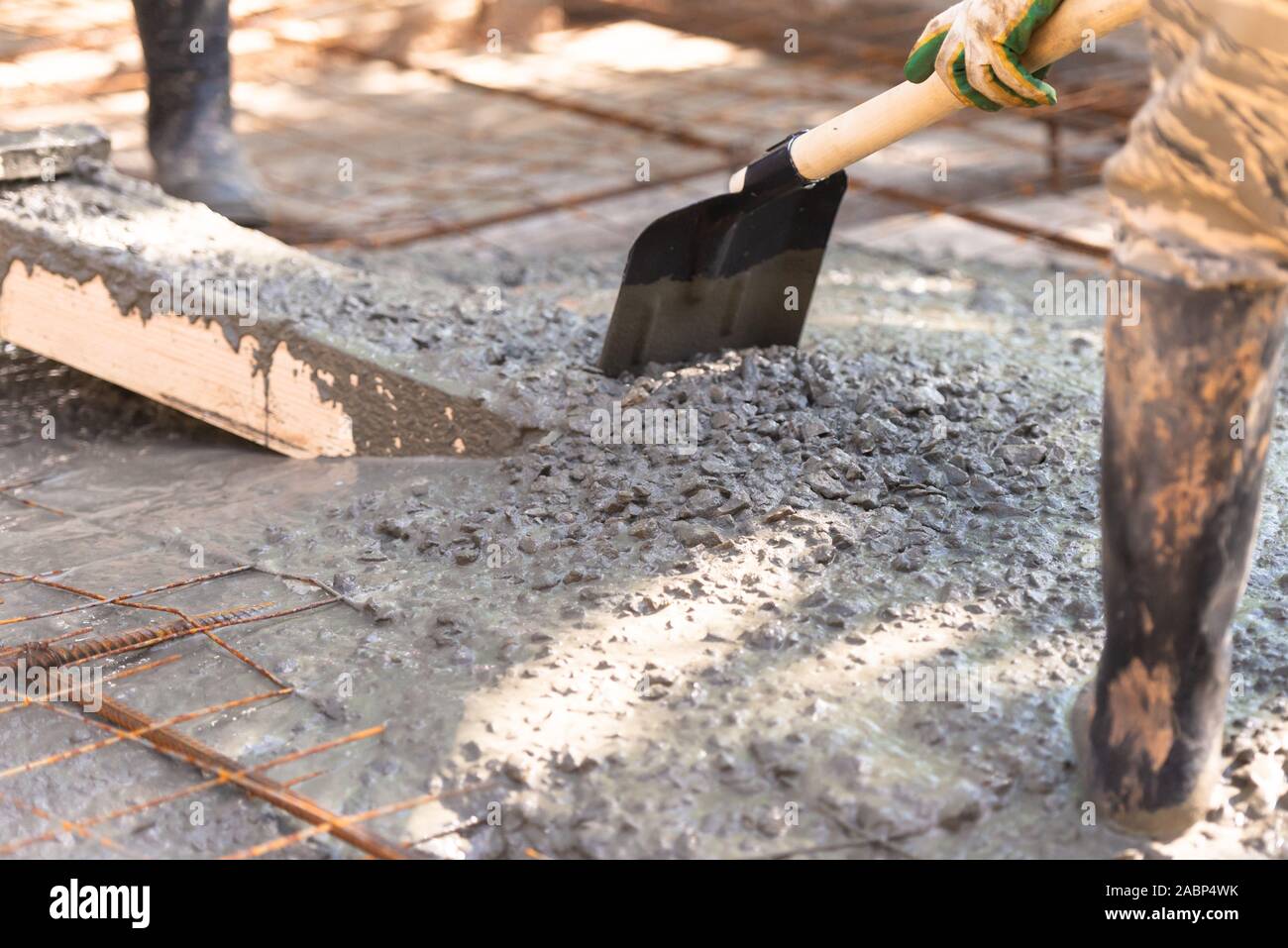 Raking concrete. Concrete for parking lot construction. A worker in