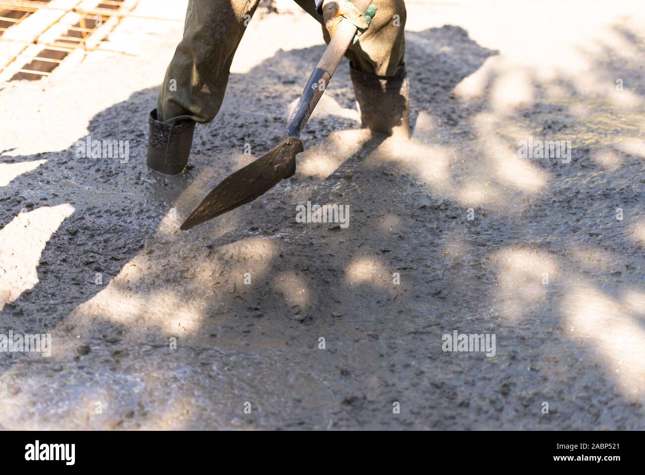 Raking concrete. Concrete for parking lot construction. A worker in