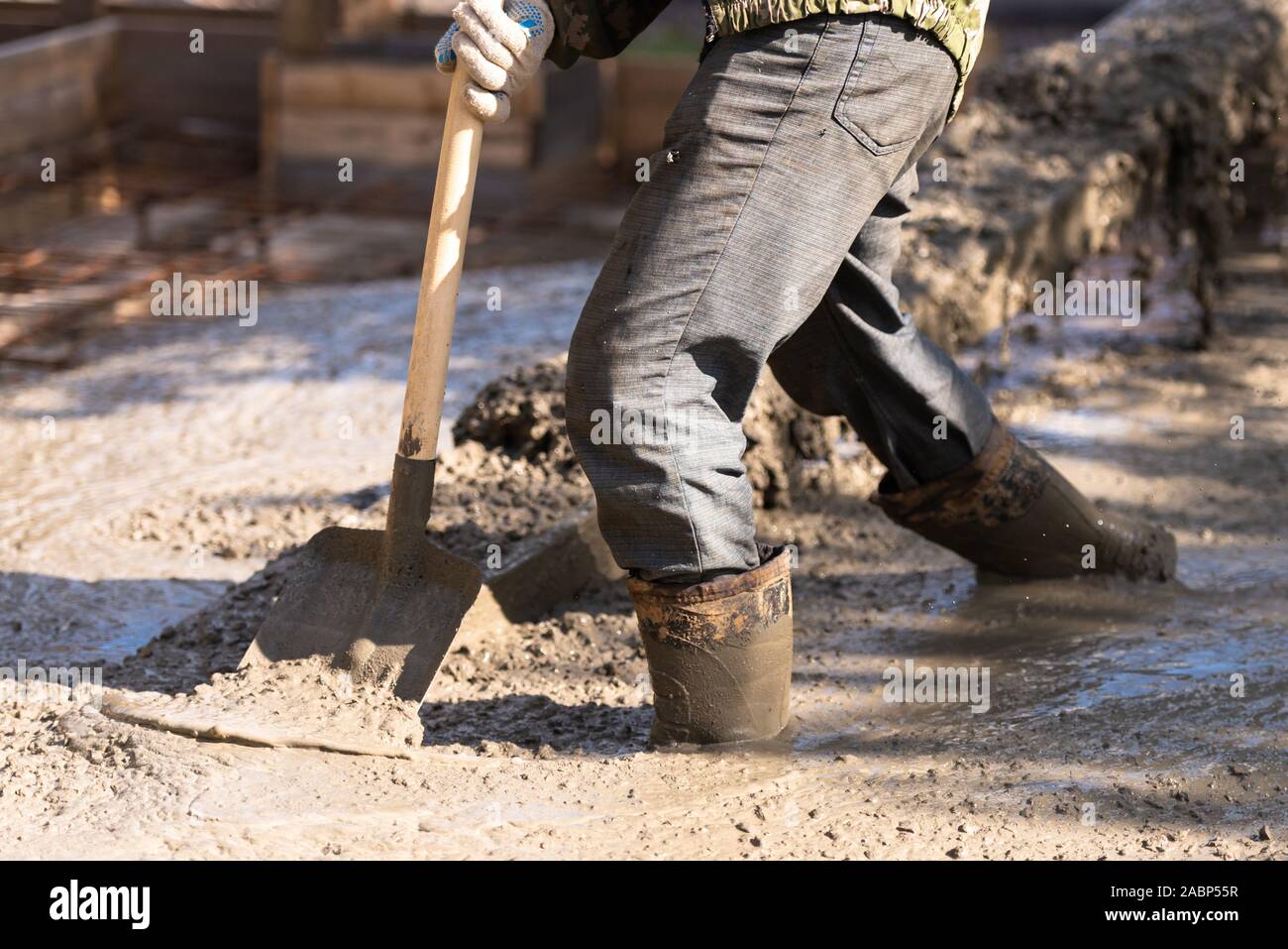 Raking concrete. Concrete for parking lot construction. A worker in