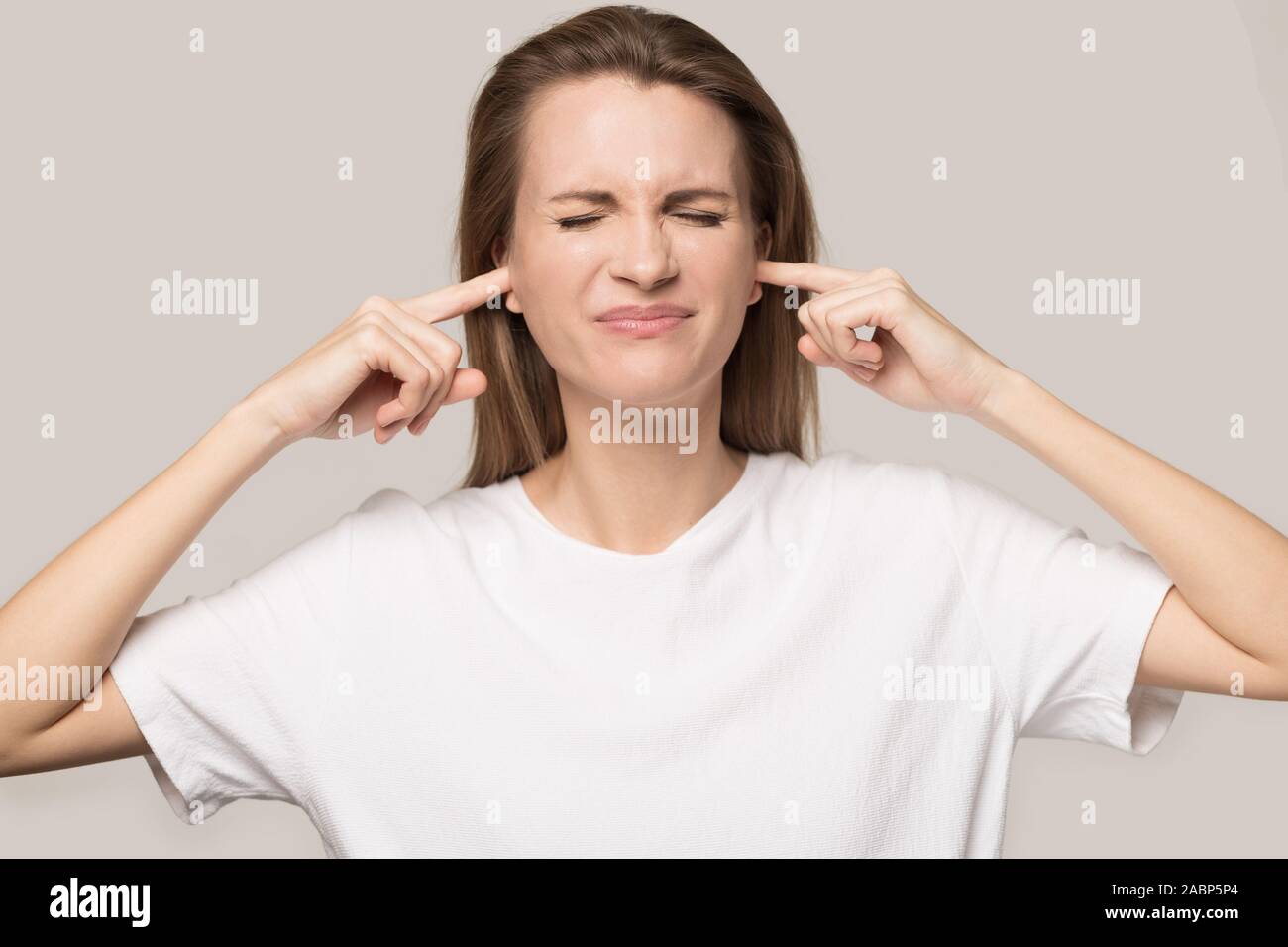 Annoyed unhappy woman plug ears with fingers, avoid loud noise Stock