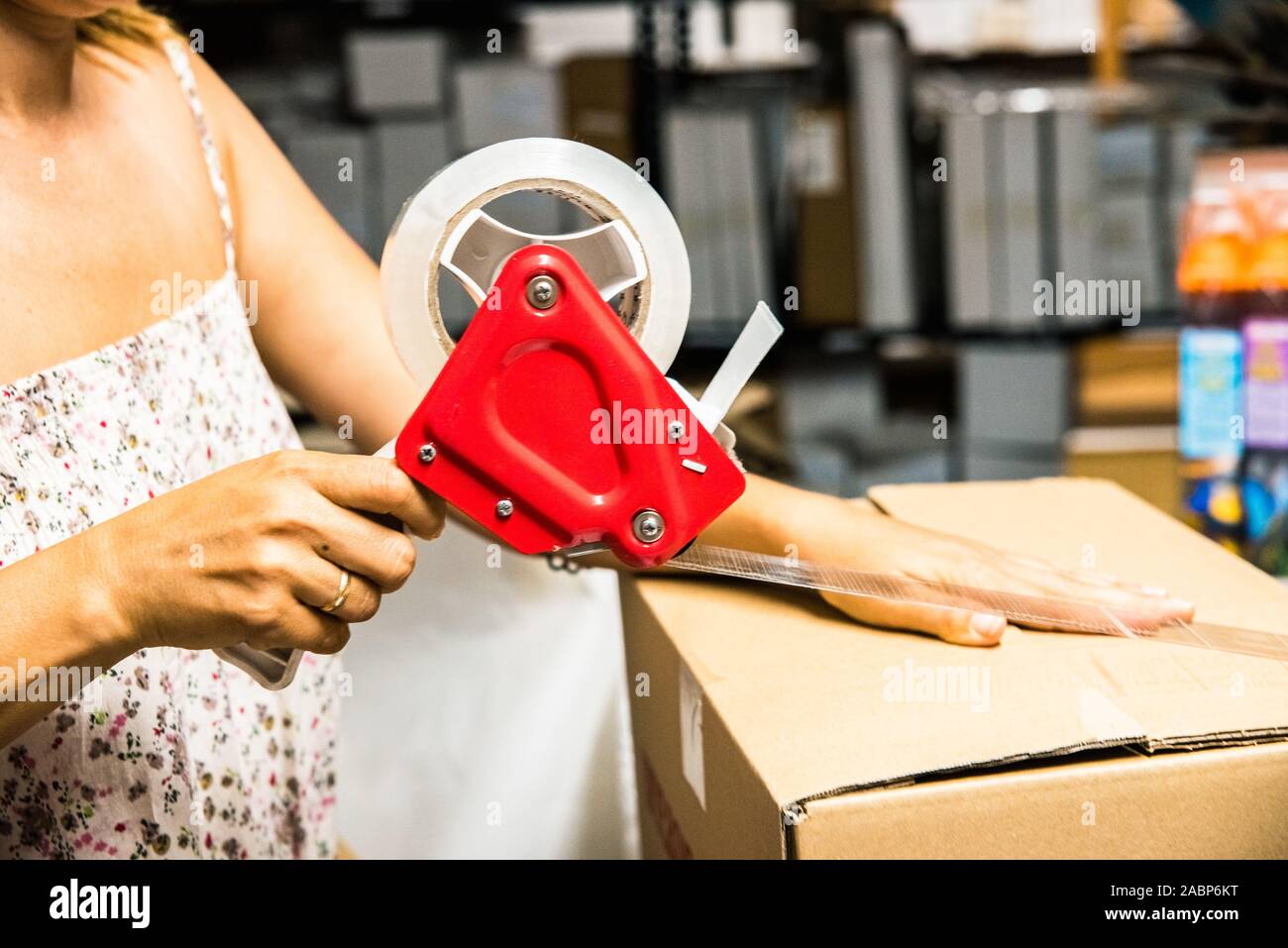 Employee of an online store closes a cardboard box with adhesive tape
