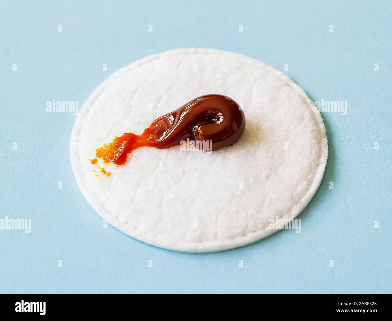 An iodine ointment on a cotton pad over a blue background. The salve is