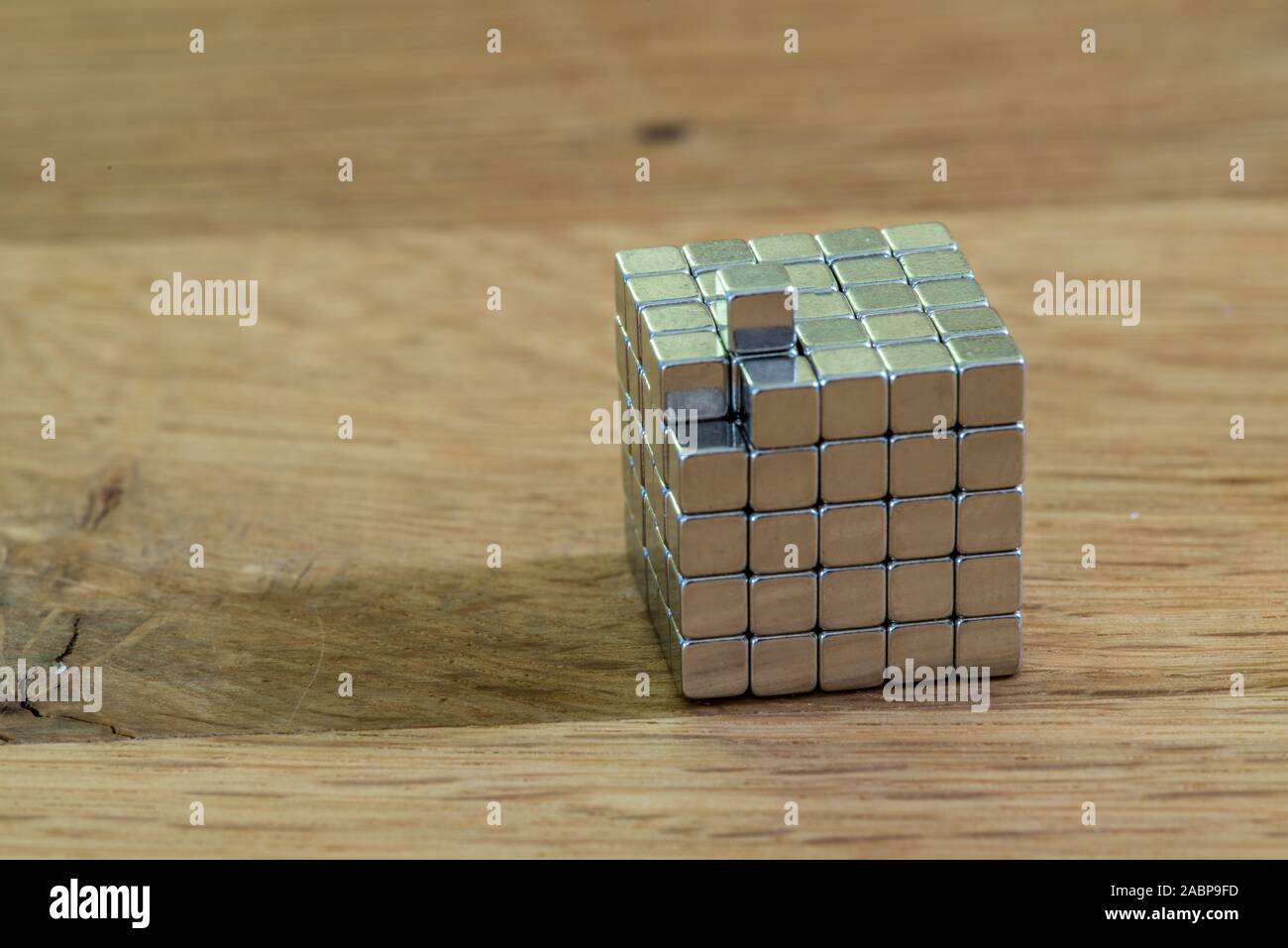 metal ball in a cube of square magnets thinking out of the box Stock Photo  - Alamy